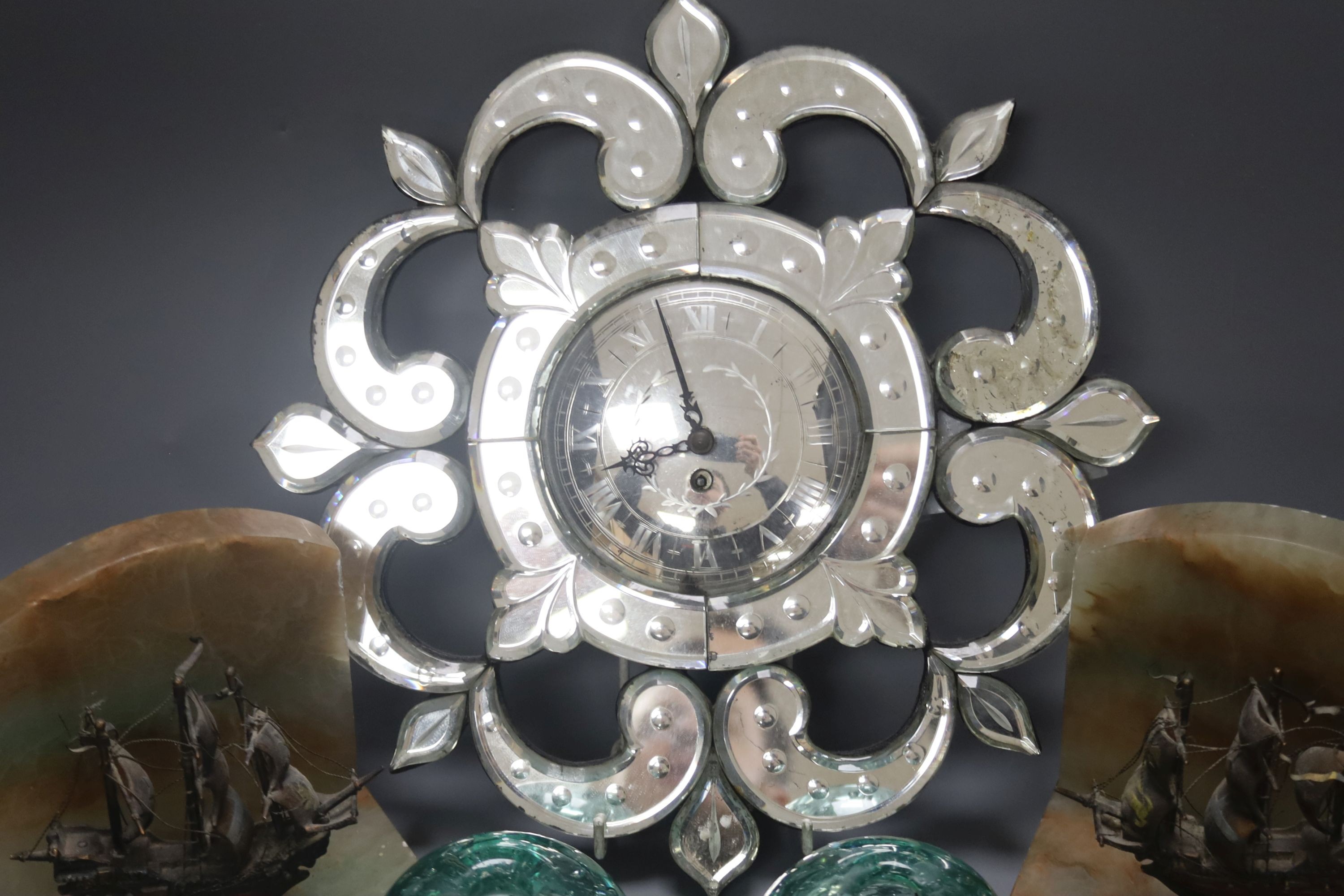 A small Venetian mirrored glass wall clock and a pair of green glass ‘candleholder’ dumps and a pair of ship bookends 33cm